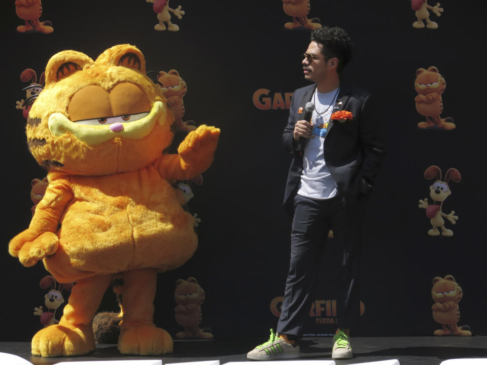 El actor de doblaje Guillermo "Memo" Villegas junto a un artista disfrazados del personaje Garfield en la alfombra naranja de la versión en español para Latinoamérica de "The Garfield Movie" en la Ciudad de México el domingo 28 de abril de 2024. (Foto AP/Berenice Bautista)