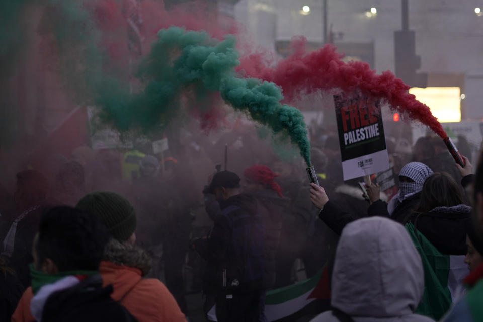 Flares are let off by protesters as others hold flags and placards during a pro-Palestinian demonstration in Trafalgar Square in London, Saturday, Nov. 25, 2023. (AP Photo/Alberto Pezzali)