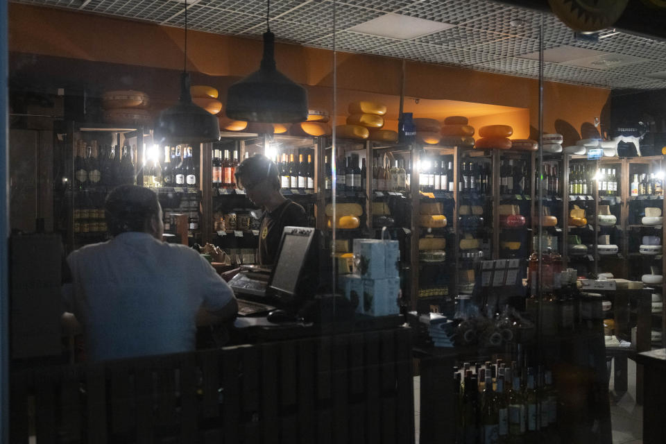 A seller works under emergency lighting during a power outage in an underground shopping mall in central Kyiv, Ukraine, Wednesday, June 19, 2024. Russian regular massive missile attacks against Ukraine's energy facilities have resulted in electricity supply restrictions having been applied throughout the country. (AP Photo/Efrem Lukatsky)