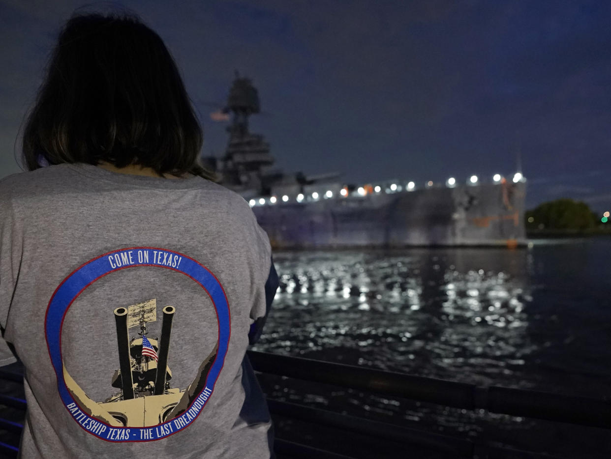 Michelle Austin watches as the USS Texas is moved from the dock Wednesday, Aug. 31, 2022, in La Porte, Texas. The vessel, which was commissioned in 1914 and served in both World War I and World War II, is being towed down the Houston Ship Channel to a dry dock in Galveston where it will undergo an extensive $35 million repair. (AP Photo/David J. Phillip)