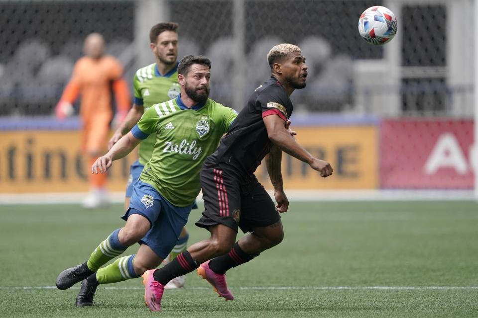 Atlanta United forward Josef Martinez, right, and Seattle Sounders midfielder Joao Paulo, center, watch the ball during the first half of an MLS soccer match, Sunday, May 23, 2021, in Seattle. (AP Photo/Ted S. Warren)