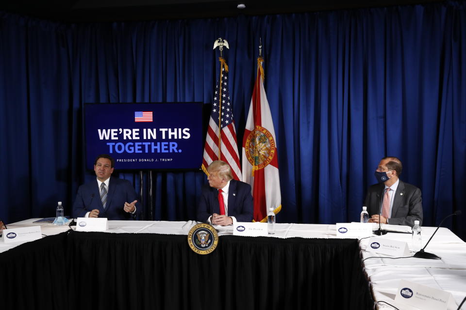 Health and Human Services Secretary Alex Azar, left, and President Donald Trump listen as Florida Gov. Ron DeSantis speaks during a roundtable discussion on the coronavirus outbreak and storm preparedness at Pelican Golf Club in Belleair, Fla., Friday, July 31, 2020. (AP Photo/Patrick Semansky)