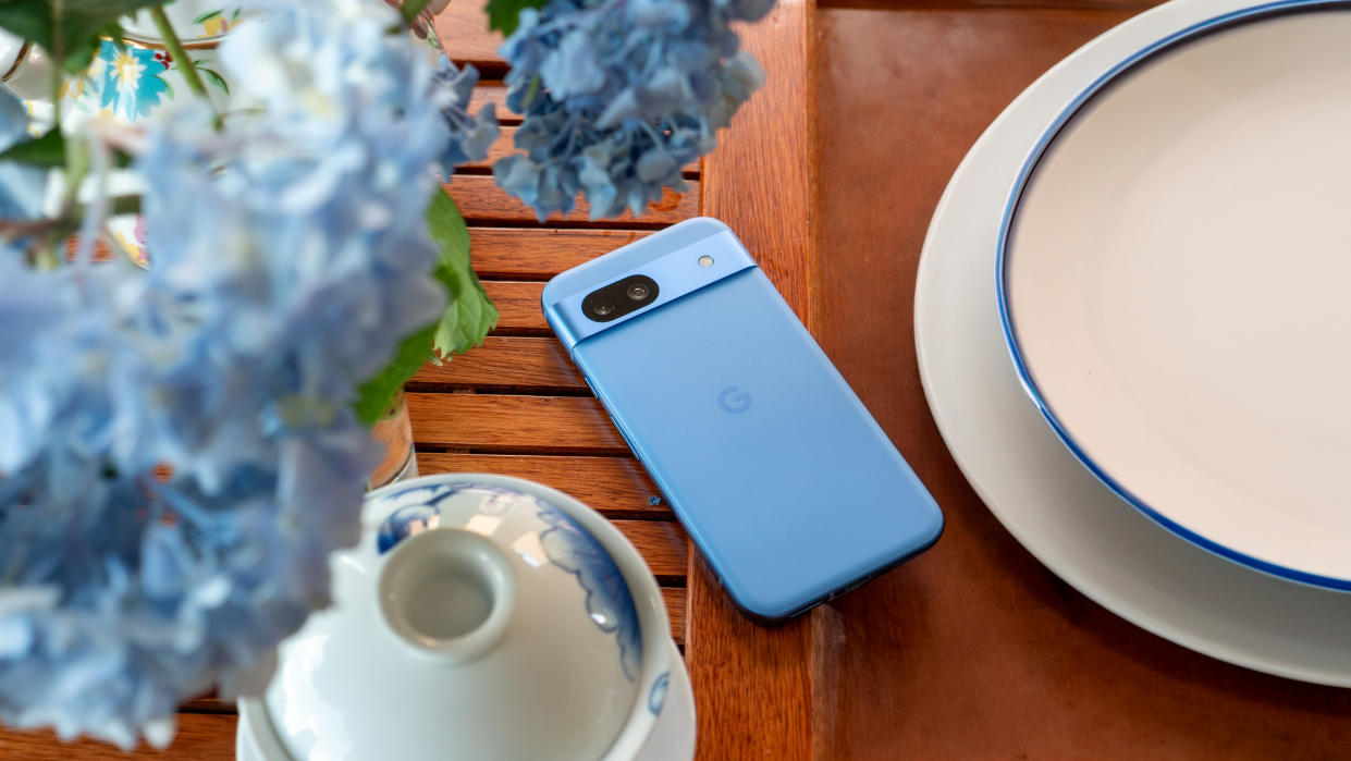  The blue Google Pixel 8a on a tea tray with blue hydrangeas above it. 