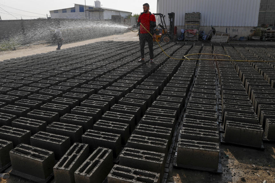 Antar al-Katatni, who runs a brick factory, sprays water on concrete bricks made from recycled rubble of war damaged buildings to be used in reconstruction efforts, in Gaza City, Wednesday, Nov. 24, 2021. The Gaza Strip has few jobs, little electricity and almost no natural resources. But after four bruising wars with Israel in just over a decade, it has lots of rubble. Local businesses are now finding ways to cash in on the chunks of smashed concrete, bricks and debris left behind by years of conflict. (AP Photo/Adel Hana)