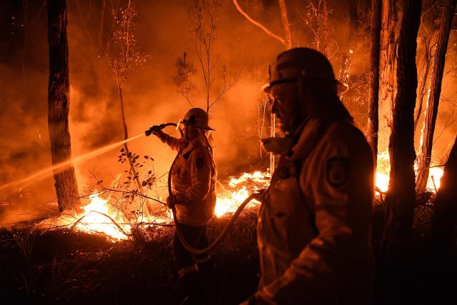 NSW RFS firefighters work through the night to prevent a flare-up from crossing the Kings Highway in between Nelligen and Batemans Bay.