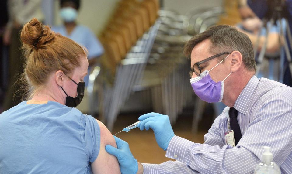 Jim Donnelly, R.N., UPMC Hamot's chief nursing and quality officer, gives a COVID-19 vaccine to Hamot nurse Mackenzie Troyan in this December 2020 file photo. Donnelly said the recent 'triple whammy' of COVID-19, flu and RSV appears to be on the decline.