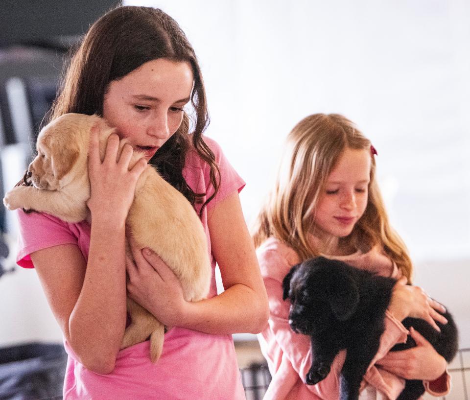 Maggie Mantooth and Celeste Oborn cuddle puppies as they visit Service Dogs Alabama, in Hope Hull on Saturday to donate money they raised by writing a book about the dogs in their neighborhood.