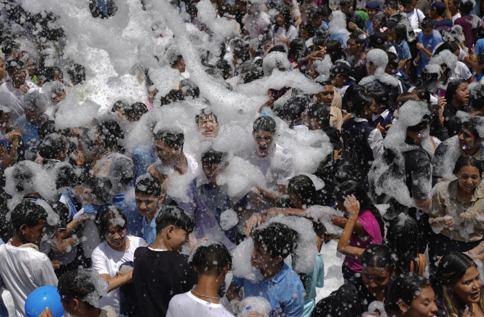 ARCHIVO - Jóvenes cubiertos de espuma durante una marcha contra sanciones estadounidenses en la que intervino el presidente, Nicolás Maduro, en Caracas, Venezuela, el 17 de mayo de 2024. (AP Foto/Ariana Cubillos, Archivo)