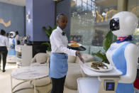 Robotic waiter Claire, receives an order from a human waiter to deliver to customers at the Robot Cafe in Nairobi, Kenya Thursday, Aug. 29, 2024. The three robots, christened Claire, R24 and Nadia, are not programmed to have a full conversation with customers, but they can say "Your order is ready, Welcome" then people have to press an exit button after picking up their food from the tray. (AP Photo/Brian Inganga)