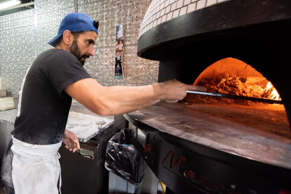 Owner Roberto Carollo places a pizza into the oven at Spuntino Wood Fired Pizzeria, in Doylestown Borough, on Tuesday, September 5, 2023.