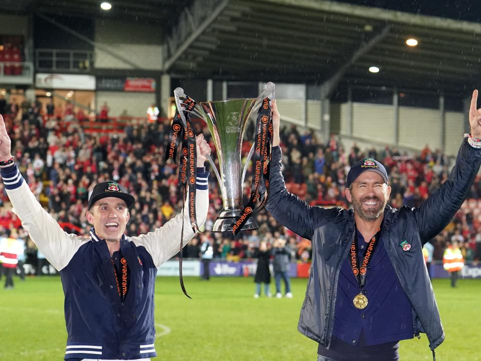 Wrexham co-owners Rob McElhenney and Ryan Reynolds celebrate with the trophy following promotion to the EFL following the Vanarama National League match at The Racecourse Ground, Wrexham on Saturday April 22, 2023.