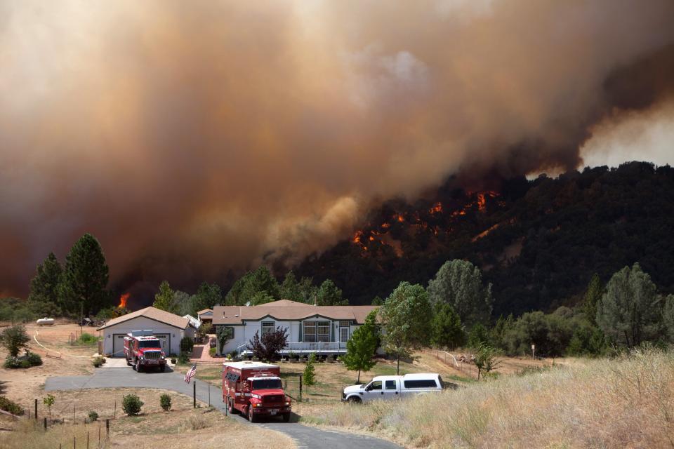 Firefighters protect an evacuated home while the "Sand Fire" burns behind, near Plymouth, California