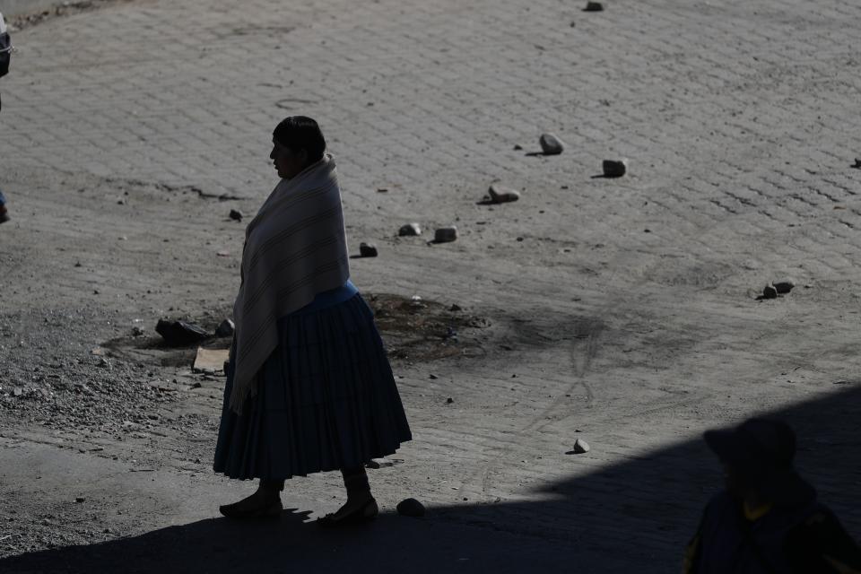 A woman walks on a highway littered with stones to block the road to the Senkata fuel plant, in El Alto, on the outskirts of La Paz, Bolivia, Wednesday, Nov. 20, 2019. Bolivia has been in a state of turbulence since a disputed Oct. 20 vote. Morales resigned Nov. 10, but his supporters oppose the interim government that took his place. (AP Photo/Natacha Pisarenko)