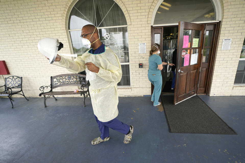 Dr. Robin Armstrong puts on his face shield while demonstrating his full personal protective equipment outside the entrance to The Resort at Texas City nursing home, where he is the medical director, Tuesday, April 7, 2020, in Texas City, Texas. Armstrong is treating nearly 30 residents of the nursing home with the anti-malaria drug hydroxychloroquine, which is unproven against COVID-19 even as President Donald Trump heavily promotes it as a possible treatment. Armstrong said Trump's championing of the drug is giving doctors more access to try it on coronavirus patients. More than 80 residents and workers have tested positive for coronavirus at the nursing home. (AP Photo/David J. Phillip)