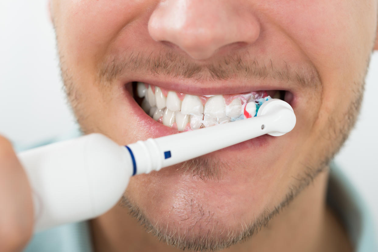 Close-up Of Young Man Teeth With Electric Toothbrush