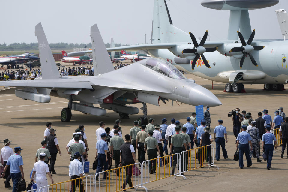Invited guests and military officers walk past the J-16D on display during the 13th China International Aviation and Aerospace Exhibition, also known as Airshow China 2021, on Tuesday, Sept. 28, 2021, in Zhuhai in southern China's Guangdong province. The PLA's air force displayed the J-16D electronic warfare airplane for the first time, according to the official China News Service. (AP Photo/Ng Han Guan)
