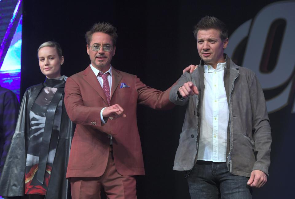 Robert Downey Jr. (C) and Jeremy Renner (R) gesture as Brie Larson (L) looks on during Marvel Studios' 