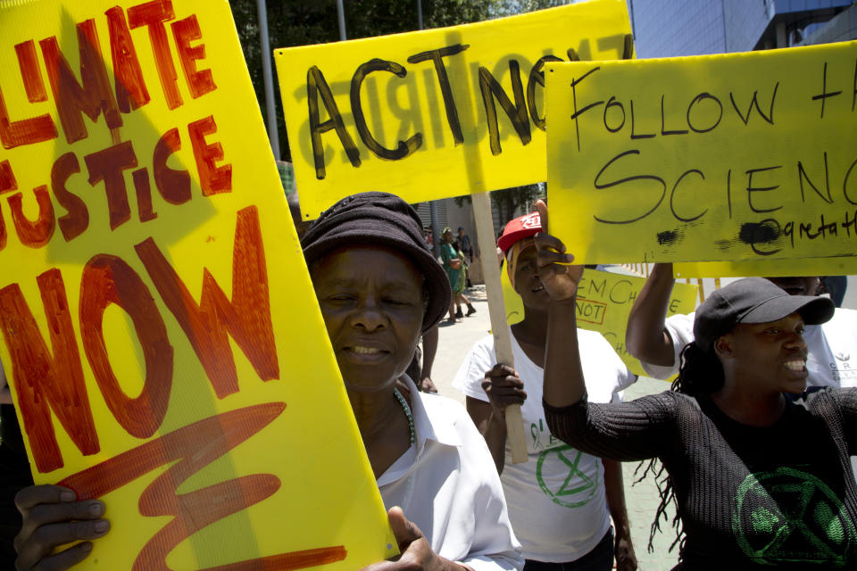 Demonstrator show their placards during climate change protest outside the Johannesburg Stock Exchange in Johannesburg, South Africa, Friday, Nov. 29, 2019. Environmentalists around the world are joining a global day of protests Friday, in a symbolic gesture to demand that governments act against climate change. (AP Photo/Denis Farrell)