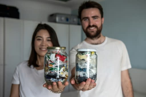 Carrie Yu and Joe Harvey, founders of zero-waste shop The Bulk House, pose with jars containing all of their personal waste collected over three months at their home in Beijing