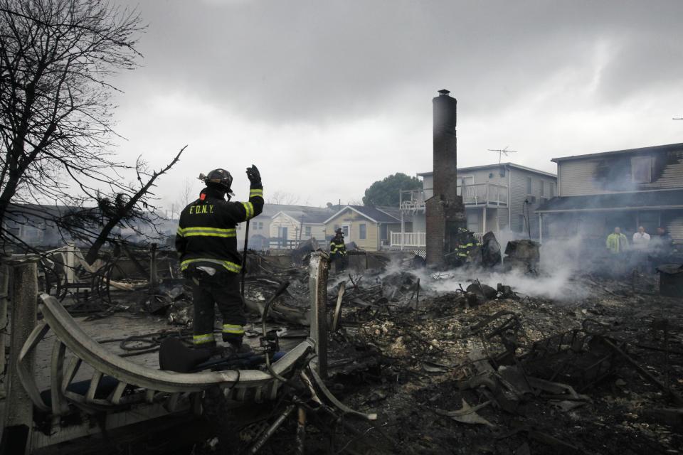 A fire fighter surveys the smoldering ruins of a house in the Breezy Point section of New York, Tuesday, Oct. 30, 2012. More than 50 homes were destroyed in a fire which swept through the oceanfront  community during superstorm Sandy. (AP Photo/Mark Lennihan)