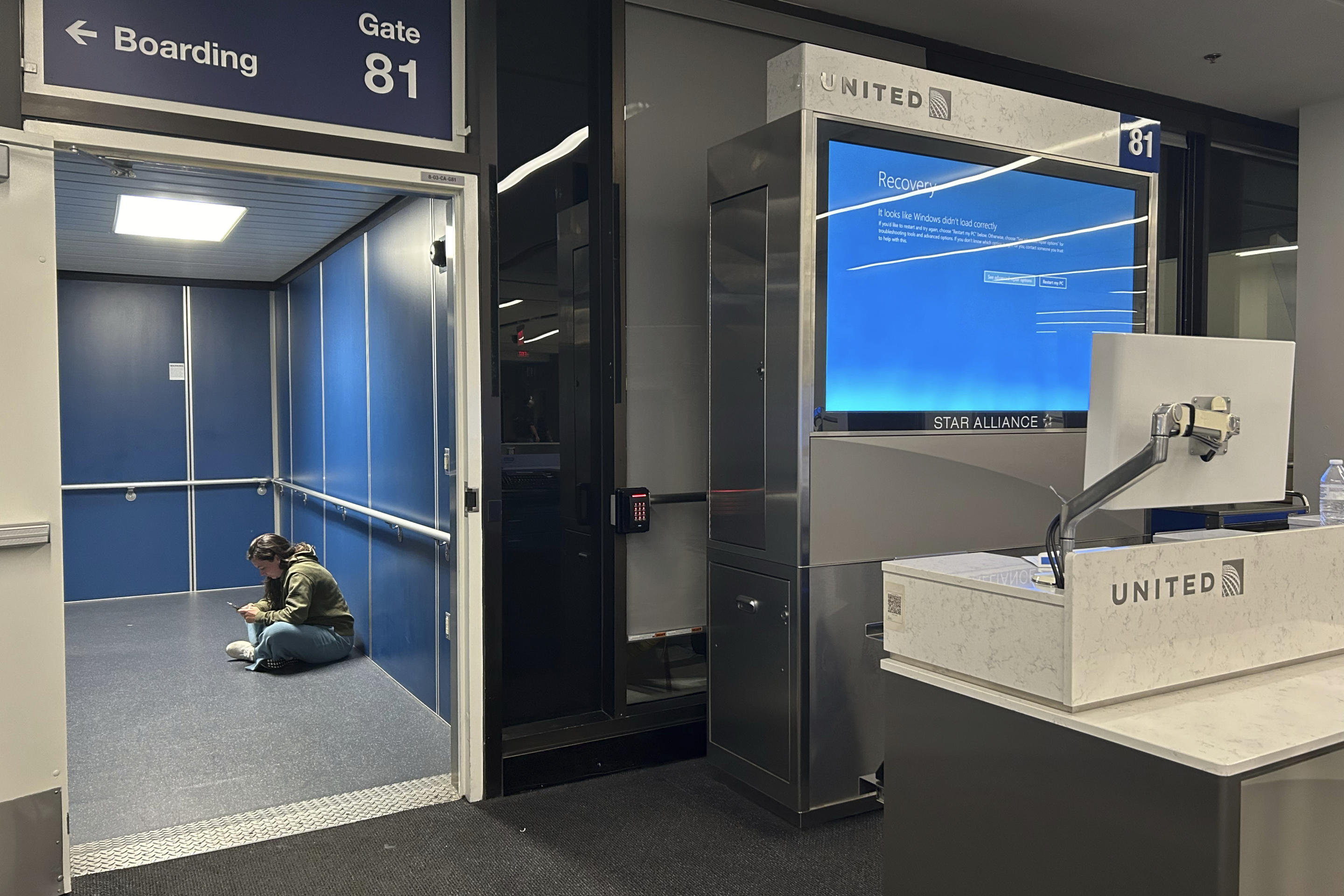 A traveler at Los Angeles International Airport sits on the floor of a jetway.