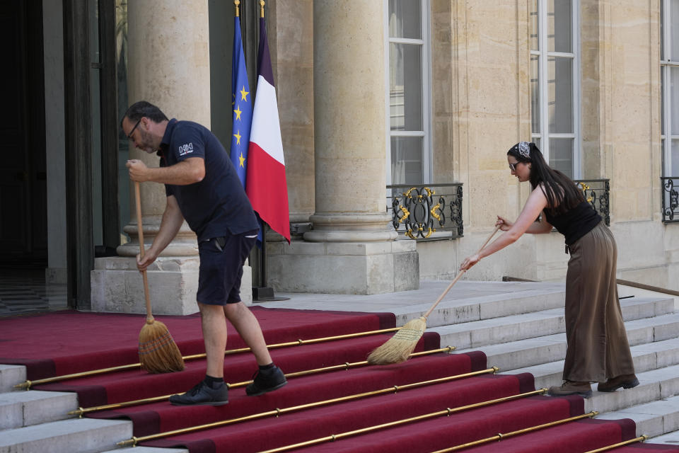 Elysee Palace employees clean the red carpet before Saudi Crown Prince Mohammed bin Salman's arrival Friday, June 16, 2023 in Paris. Saudi Crown Prince Mohammed bin Salman is to meet with French President Emmanuel Macron as part of an official visit, during which he will also participate in a global financing summit aimed at fighting poverty and climate change. (AP Photo/Michel Euler)