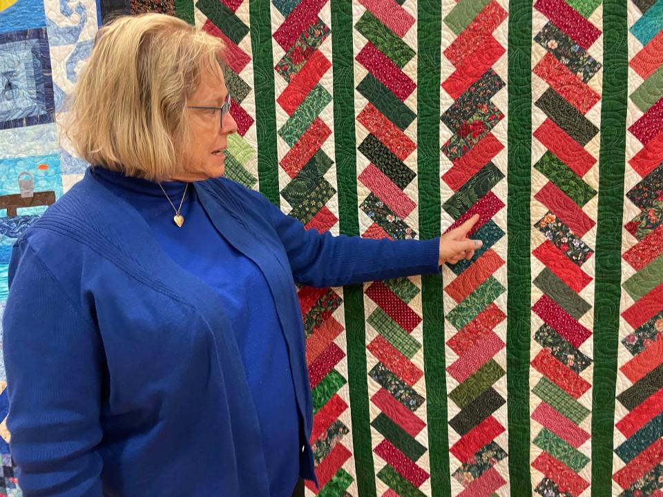 Quilter Brenda Young Ferrell points out the stitching on her quilt “Stacked Bricks.”