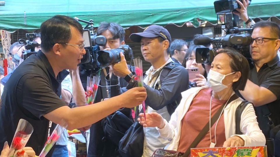 民眾黨立委黃國昌（前左）11日上午到新北市板橋區福德市場發送康乃馨給民眾。中央社