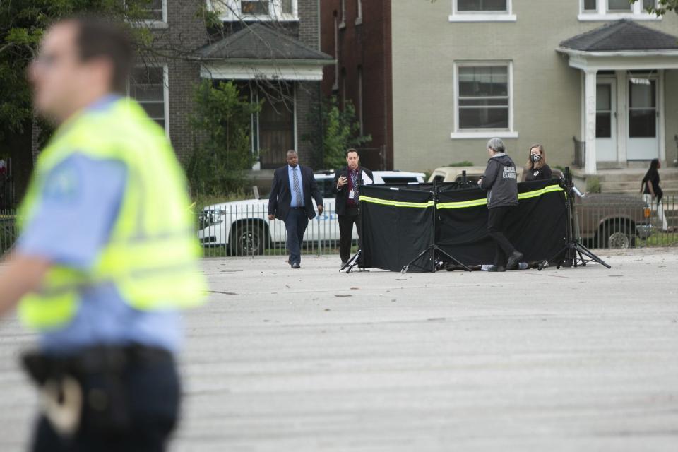 A St. Louis police officer conducting crowd control tries to keep people from entering the crime scene where officers and crime lab investigators covered the body of a shooting victim on the courtyard of Farragut Elementary School on Monday, June 21, 2021, in the Greater Ville neighborhood in north St. Louis. (Daniel Shular/St. Louis Post-Dispatch via AP)