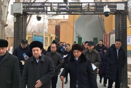 FILE PHOTO: Imams and government officials pass under security cameras as they leave the Id Kah Mosque during a government organised trip in Kashgar