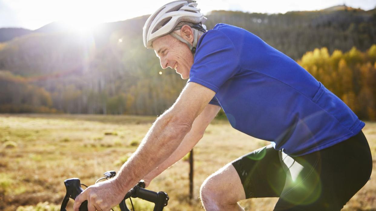 longevity tests side view of smiling senior man riding bicycle during sunny day