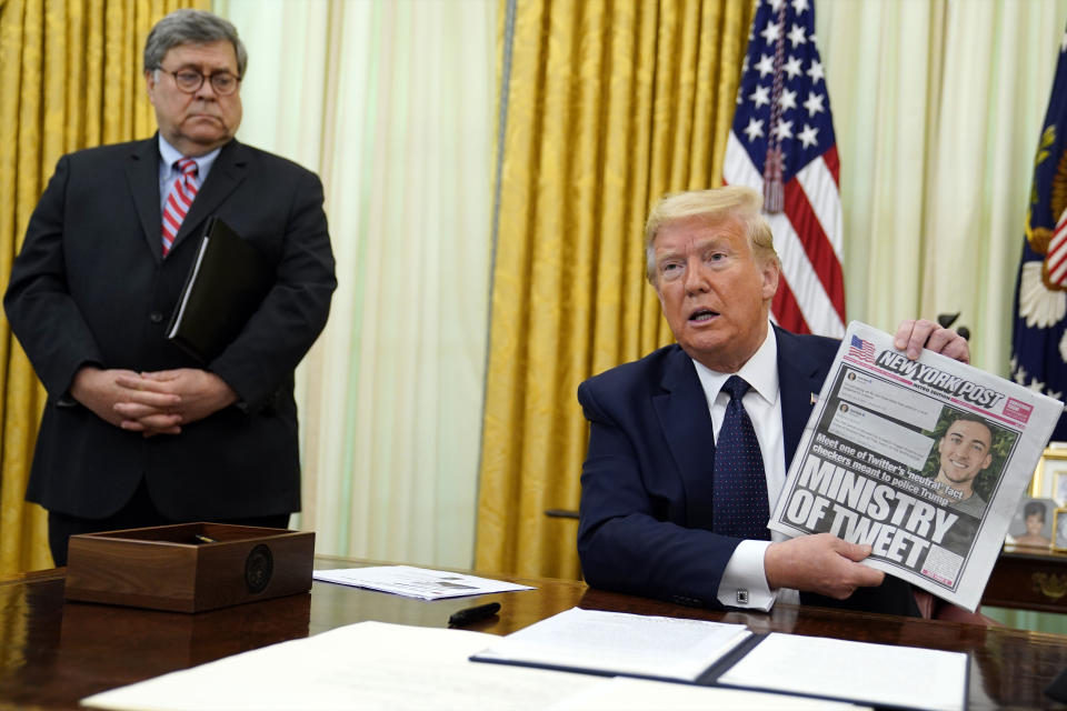 President Donald Trump holds up a copy of the New York Post as speaks before signing an executive order aimed at curbing protections for social media giants, in the Oval Office of the White House, Thursday, May 28, 2020, in Washington, as Attorney General William Barr watches. (AP Photo/Evan Vucci)