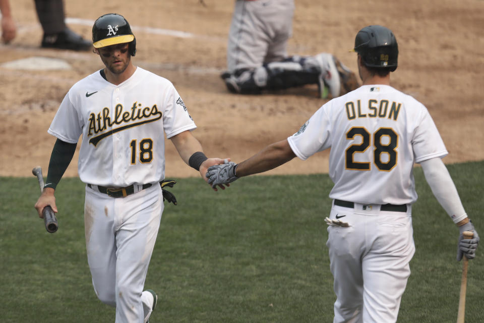 Oakland Athletics' Chad Pinder, left, celebrates with Matt Olson after scoring on a single by Ramon Laureano against the Houston Astros during the third inning of the first baseball game of a doubleheader in Oakland, Calif., Tuesday, Sept. 8, 2020. (AP Photo/Jed Jacobsohn)