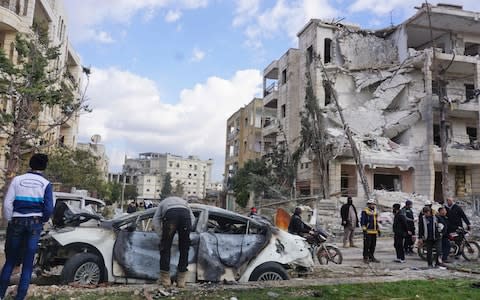 People look at the remains of a car which exploded following a double attack in Syria's jihadist-held city of Idlib, on February 18, 2019.  - Credit: MUHAMMAD HAJ KADOUR/AFP