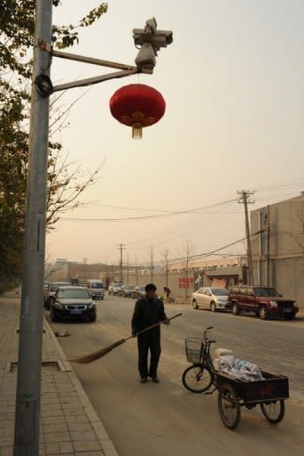 A Chinese road sweeper works under a surveillance camera watching Ai Weiwei's studio in Beijing. The dissident Chinese artist was barred from a hearing Wednesday challenging a multi-million-dollar tax order against a firm he founded, he said, accusing authorities of trying to "crush" him