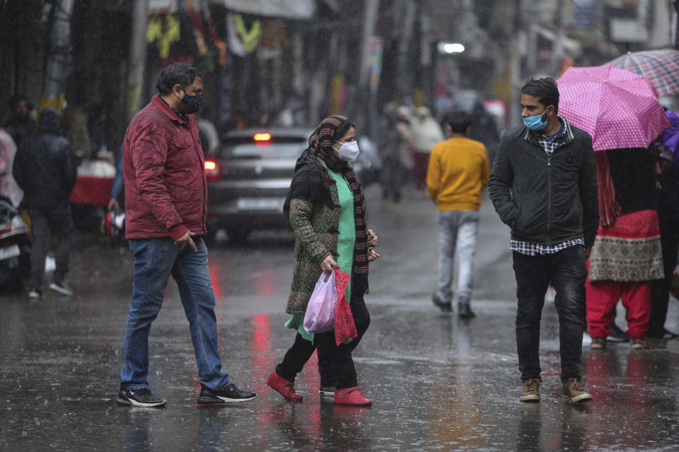 Indians, wearing face masks as a precautionary measure against the coronavirus walk at a market during rain in Jammu, India, Sunday, Jan.3, 2021. India authorized two COVID-19 vaccines on Sunday, paving the way for a huge inoculation program to stem the coronavirus pandemic in the world’s second most populous country. (AP Photo/Channi Anand)