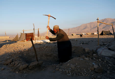 FILE PHOTO - An Afghan man who was internally displaced due to drought digs soil to set up a tent at a refugee camp in Herat province, Afghanistan October 14, 2018. REUTERS/Mohammad Ismail/File Photo