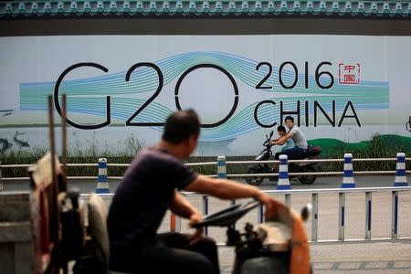 People cycle past a billboard for the upcoming G20 summit in Hangzhou, Zhejiang province, China, July 29, 2016. Picture taken July 29, 2016. REUTERS/Aly Song