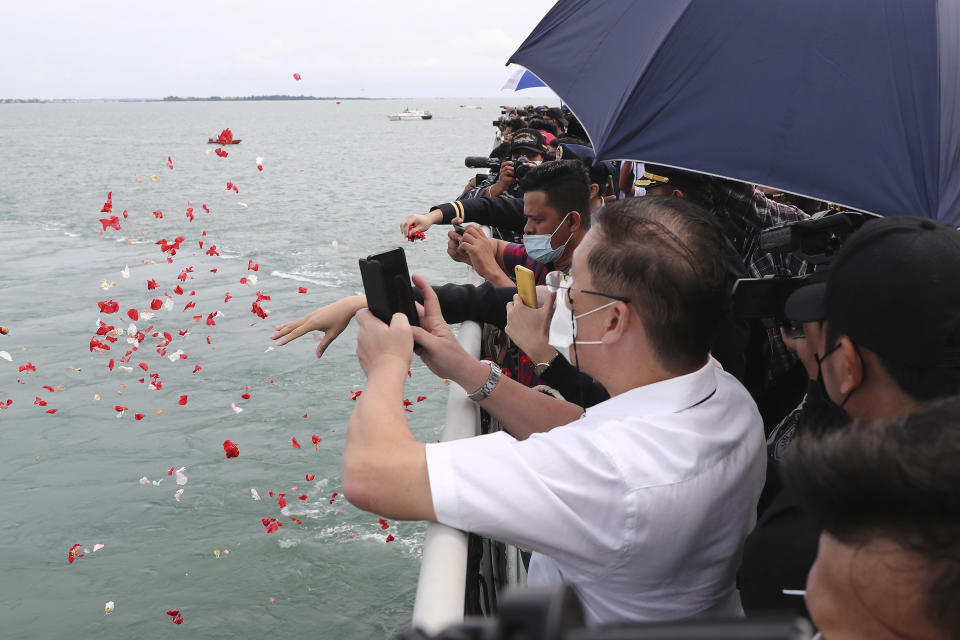 Relatives of the victims of a Sriwijaya Air Flight 182 throw flowers into the Java Sea where the plane crashed on Jan. 9 killing all of its passengers, during a memorial ceremony held on the deck of Indonesian Navy Ship KRI Semarang, near Jakarta in Indonesia, Friday, Jan. 22, 2021. (AP Photo/Tatan Syuflana)