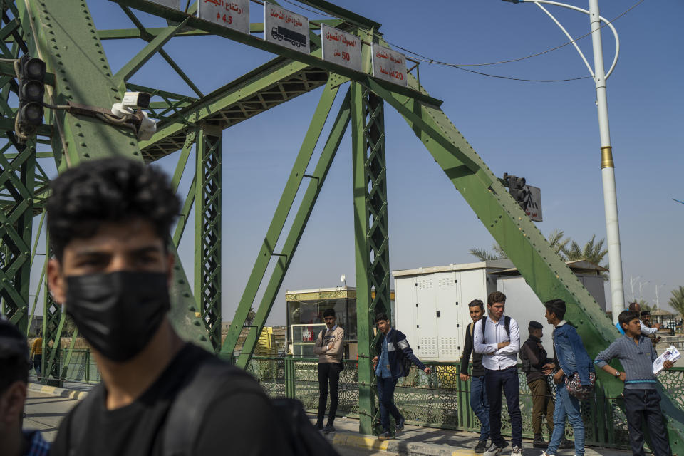 Youths wait for a ride on the bridge crossing the Euphrates River in Fallujah, Iraq, Thursday, March 2, 2023. In 2004, four armed contractors working for the private military contractor Blackwater were killed and their bodies hung from the bridge. (AP Photo/Jerome Delay)