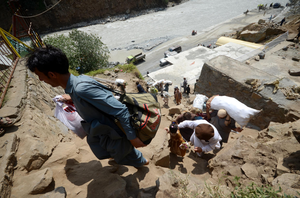 People carry food on their backs due to flood-destroyed bridges and roads in Swat, Pakistan