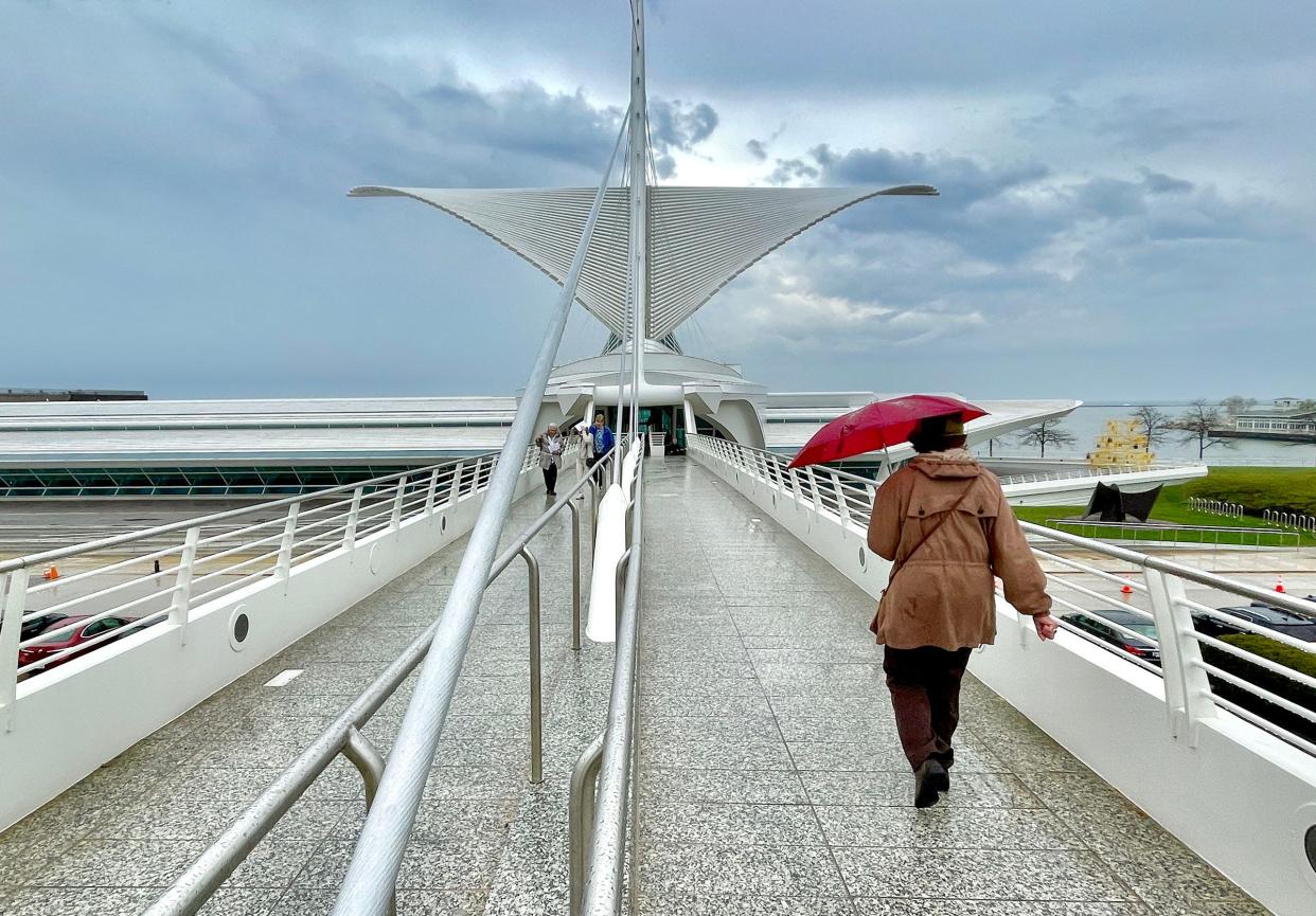 A woman walks with her umbrella over the bridge to the Milwaukee Art Museum, April 20, 2023.