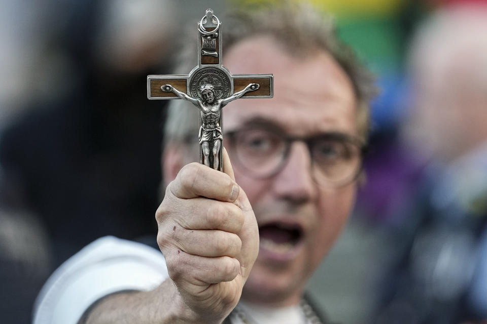 A man protests against a public blessing ceremony with a crucifix in his hand in front of the Cologne Cathedral in Cologne, Germany, Wednesday, Sept. 20, 2023. Several Catholic priests have held a ceremony blessing same-sex couples outside Cologne cathedral in a protest against the city’s conservative archbishop Cardinal Rainer Maria Woelki. (AP Photo/Martin Meissner)