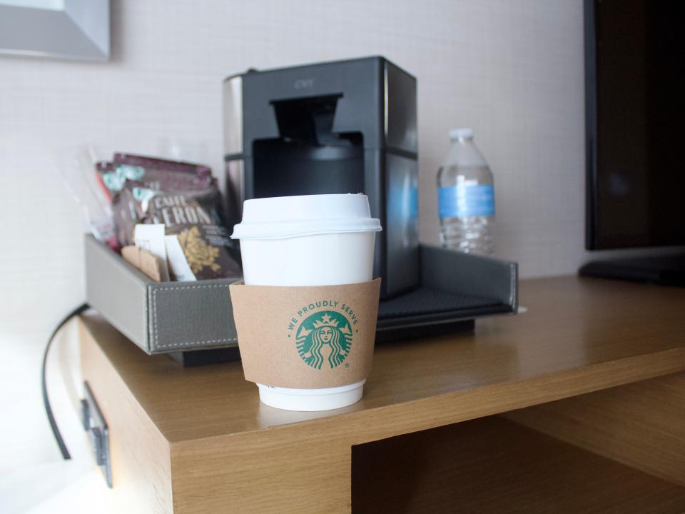 View of a coffee cup with a cardboard sleeve bearing the Starbucks logo.