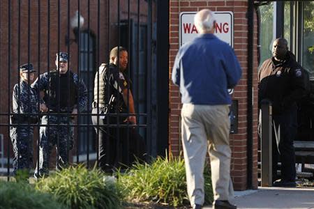 A Navy Yard personnel approaches a security checkpoint as he returns to work two days after a gunman killed 12 people before police shot him dead, in Washington, September 18, 2013. REUTERS/Jonathan Ernst