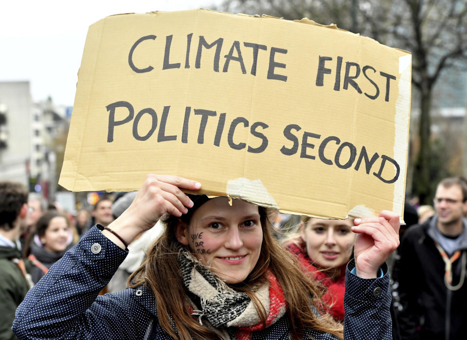 A demonstrator holds a placard which reads 'climate first, politics second' during a 'Claim the Climate' march in Brussels, Sunday, Dec. 2, 2018. The climate change conference, COP24, will take place in Poland from Dec. 2-14. (AP Photo/Geert Vanden Wijngaert)