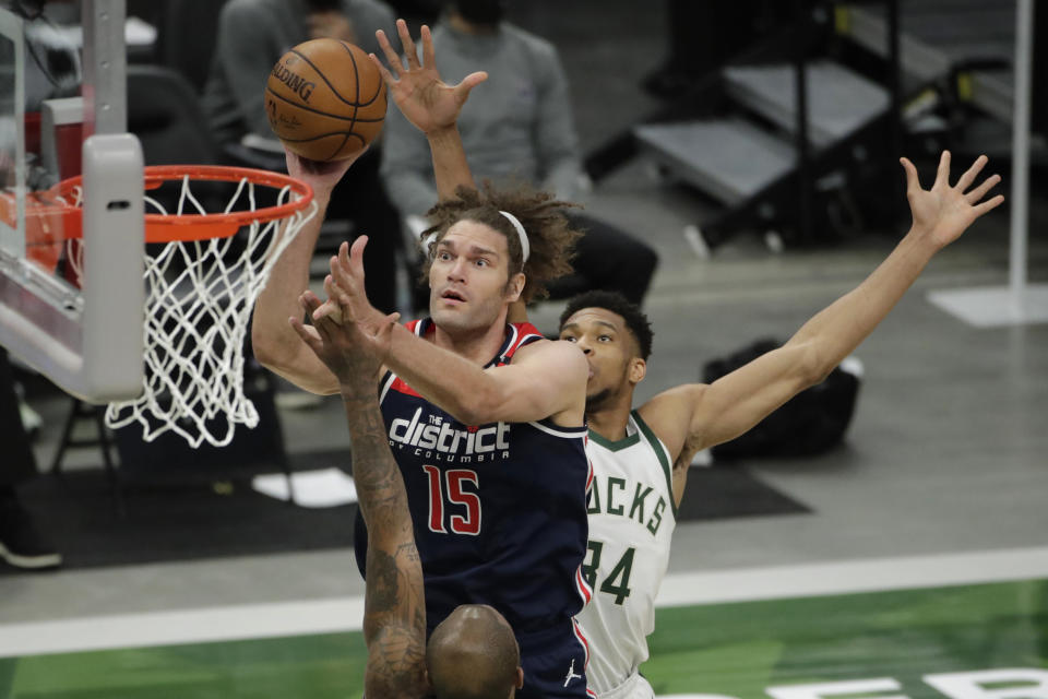 Washington Wizards' Robin Lopez (15) shoots between Milwaukee Bucks' P.J. Tucker and Giannis Antetokounmpo, right, during the first half of an NBA basketball game Wednesday, May 5, 2021, in Milwaukee. (AP Photo/Aaron Gash)