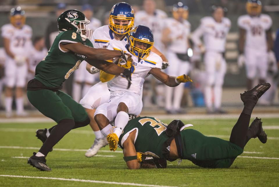 South Dakota State wide receiver Tyler Feldkamp, center, holds on to the ball as he's taken down by Sacramento State safety Marcus Aponte, left, and linebacker Armon Bailey (30) after bobbling a kickoff return during the third quarter of a second-round NCAA FCS college football playoff game Saturday, Dec. 4, 2021, in Sacramento, Calif.