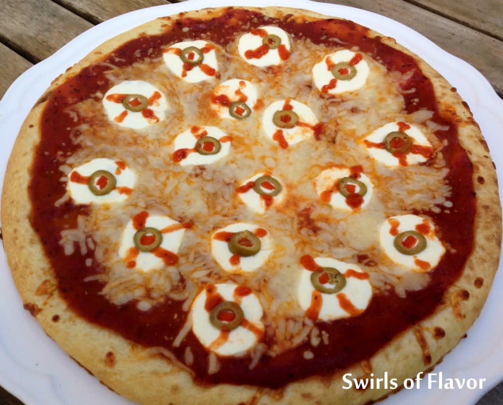 <p>Swirls of Flavor</p><p>Ghoulish eyeball pizza brings pizza night up to a whole new level with fresh mozzarella or sliced cheese and olives. Perfect for lovers of Halloween to enjoy some fun!</p><p><strong>Get the recipe here: <a href="https://swirlsofflavor.com/tbh-throw-back-halloween-bloody-eyeball-pizza/" rel="nofollow noopener" target="_blank" data-ylk="slk:Eyeball Pizza;elm:context_link;itc:0;sec:content-canvas" class="link rapid-noclick-resp">Eyeball Pizza</a></strong></p>