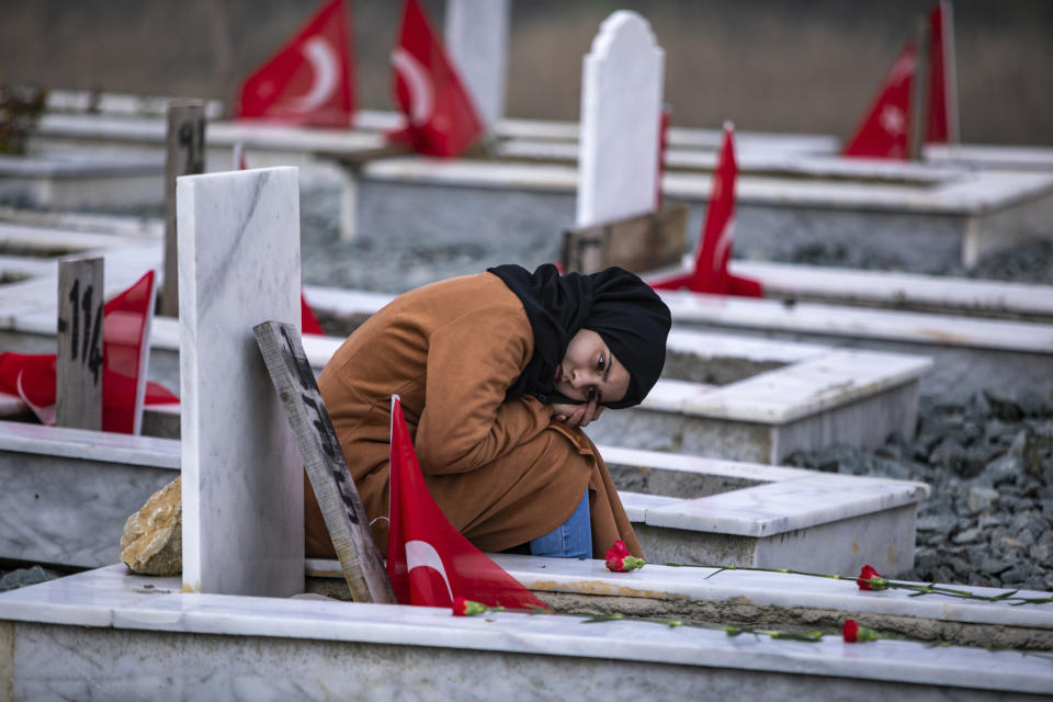 A girl sits next to a grave in a cemetery where some of the victims of the earthquake in Feb. 2023 are buried, in Antakya, southern Turkey, Tuesday, Feb. 6, 2024. Millions of people across Turkey on Tuesday mourned the loss of more than 53,000 friends, loved ones and neighbors in the country's catastrophic earthquake a year ago. (AP Photo/Metin Yoksu)